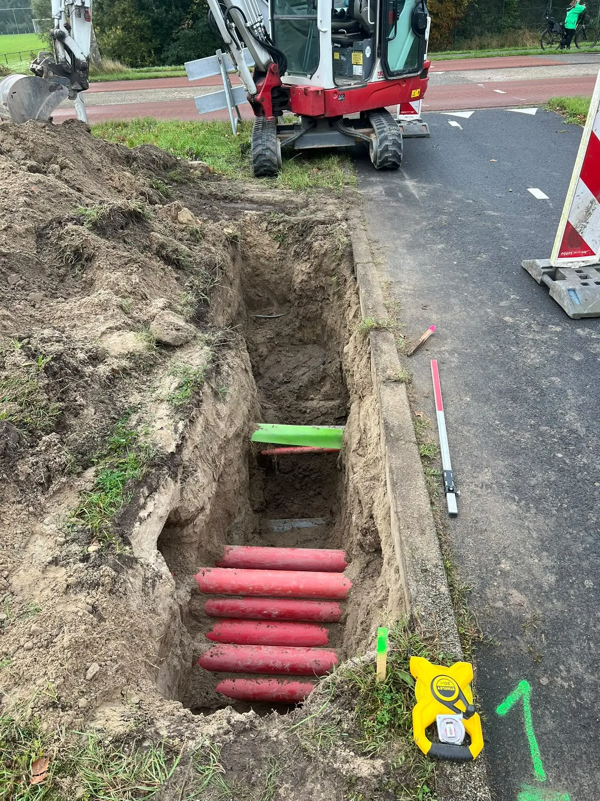 Sleuf graven met minigraver langs de weg